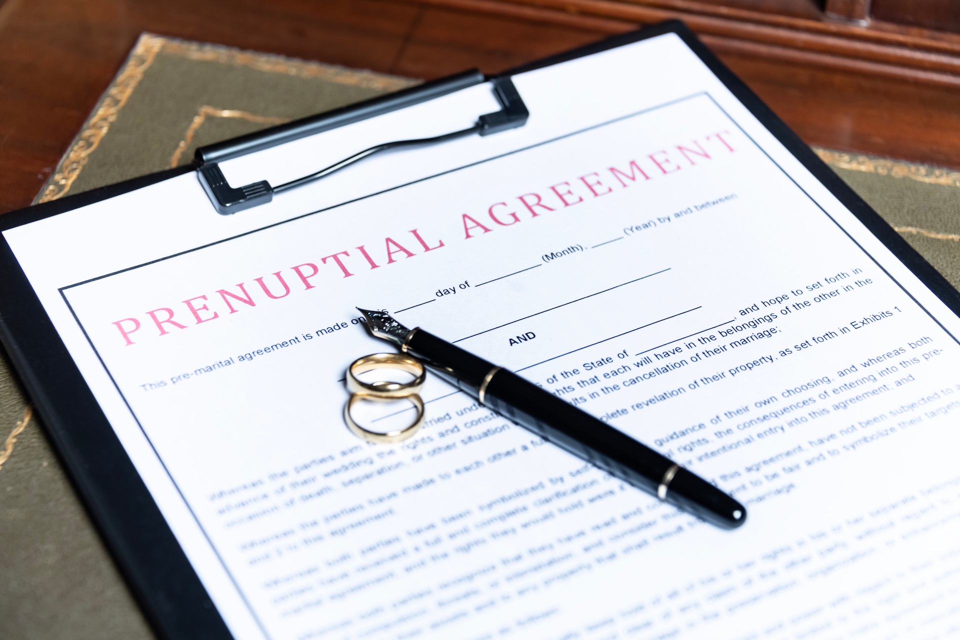 Close-up of a prenuptial agreement form with wedding rings and a fountain pen indicating the legal aspects of marriage preparation Close-up of a prenuptial agreement form with wedding rings and a fountain pen, indicating the legal aspects of marriage preparation