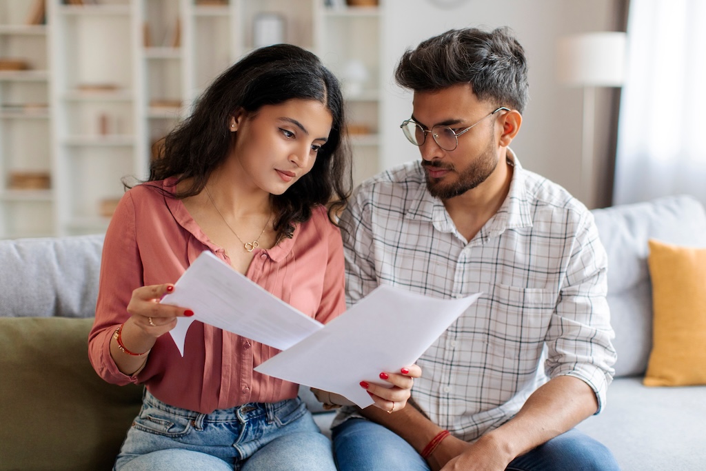 Focused separated couple checking bills, reading spousal support modification documents | Law Office of Eric Andrew Mercer Focused separated couple checking bills, reading spousal support modification documents
